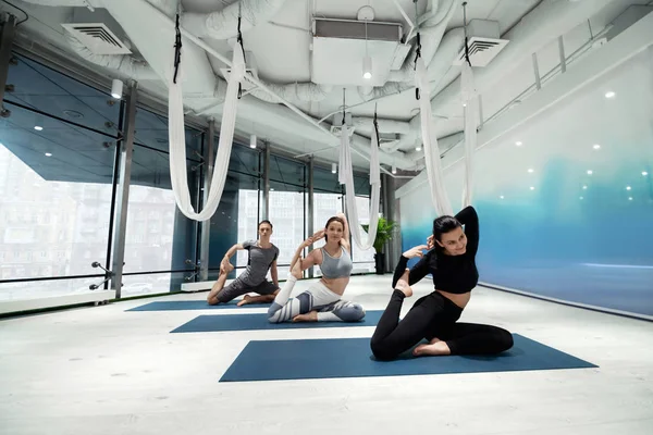 Twee vrouwen en mannen werken aan flexibiliteit terwijl ze yoga doen — Stockfoto