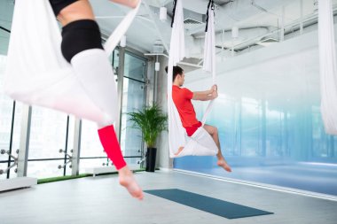 T-shirt giyen adam grup derslerine katılan hava yogası yapıyor