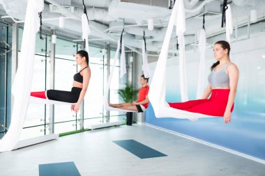 Uçan yoga yaparken hava ipek oturan iki kadın ve adam