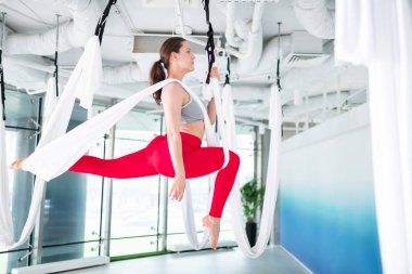 Hava yogası yapan at kuyruklu koyu saçlı kadın