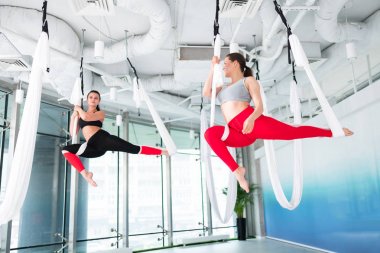 Kadın tayt giyiyor ve üst katta havadan yoga yapıyor.