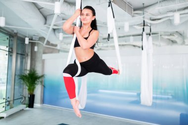 Siyah bluzlu genç, siyah saçlı kadın yerçekimi yogası yapıyor.