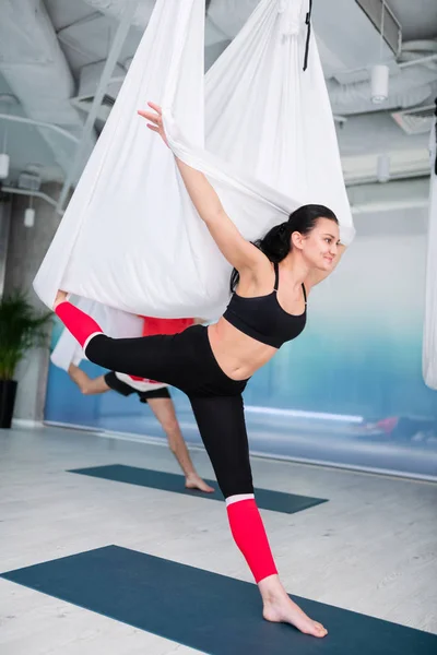 Donkerharige zakenvrouw glimlachend tijdens het uitproberen van Aerial yoga — Stockfoto