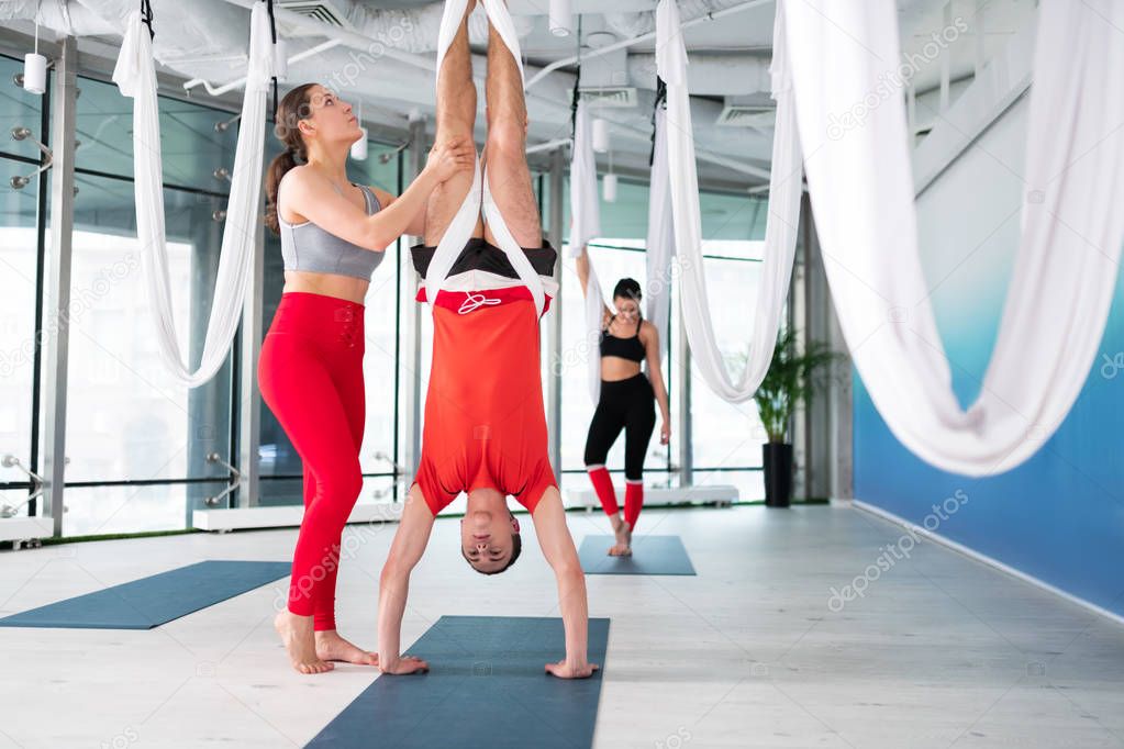 Yoga teacher in red leggings standing near her male student
