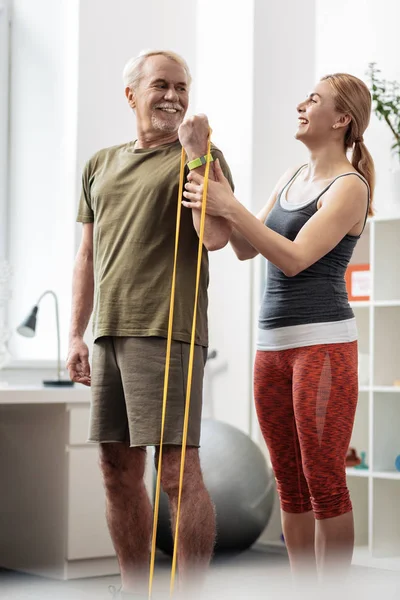 Encantado buen hombre haciendo ejercicio con una banda elástica — Foto de Stock