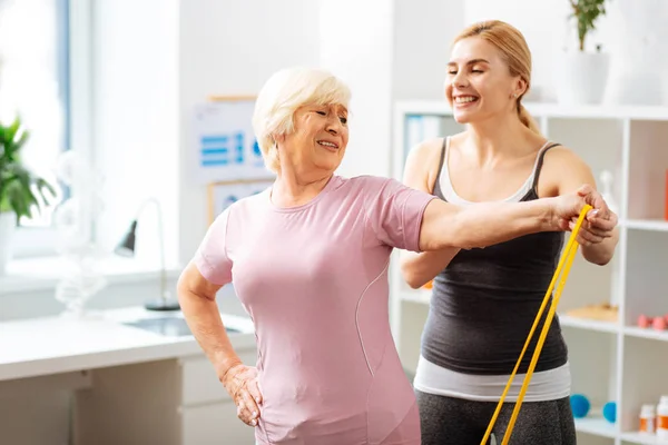 Treinamento de mulher sênior positivo com um elástico — Fotografia de Stock