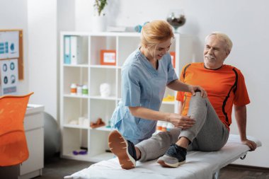 Joyful pozitif kadın hemşire bir bacak masajı yapıyor