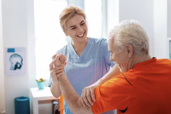 Vrolijke positieve verpleegster glimlachend naar haar patiënt — Stockfoto