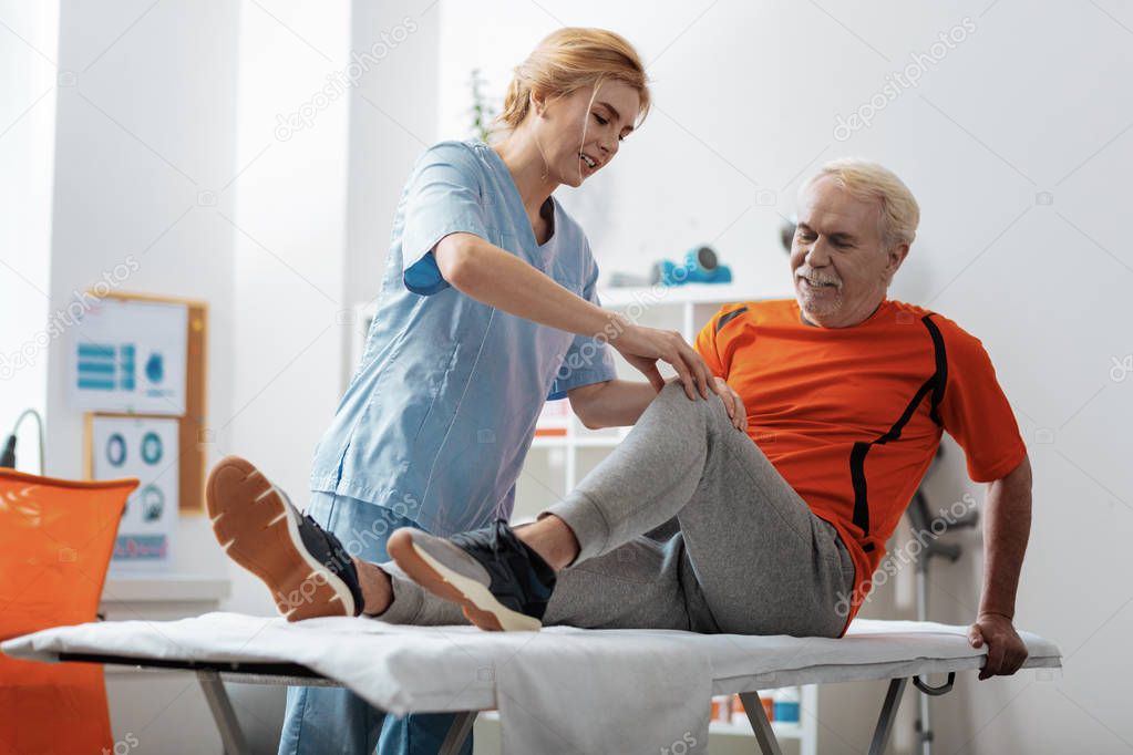 Nice blonde woman touching her patients knee