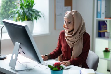 Teacher sitting at the computer while preparing the presentation