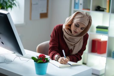 Güzel Müslüman kadın çalışırken deftere yazma