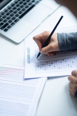 Teacher sitting near laptop correcting tests of pupils