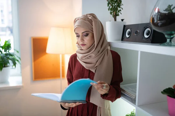 Appealing teacher wearing headscarf reading some papers — Stock Photo, Image