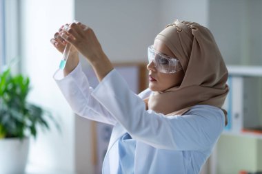 Kadın kimyager şeffaf sıvı ile test tüpü bakıyor