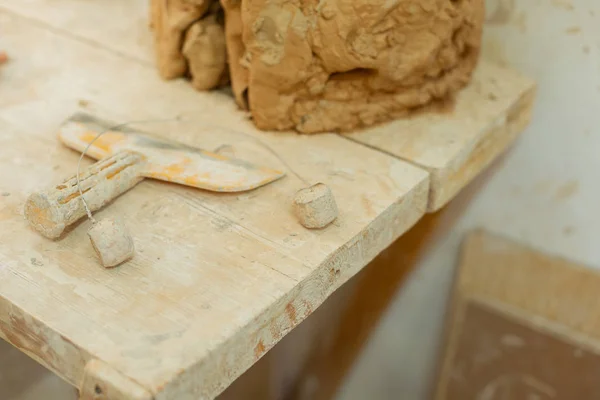 Schmutziges Metallwerkzeug, das auf einem Holztisch liegt, der mit Lehmschicht überzogen ist — Stockfoto