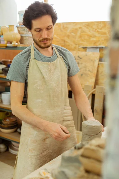 Gefocust brunette man in speciale schort meten van de benodigde hoeveelheid klei — Stockfoto