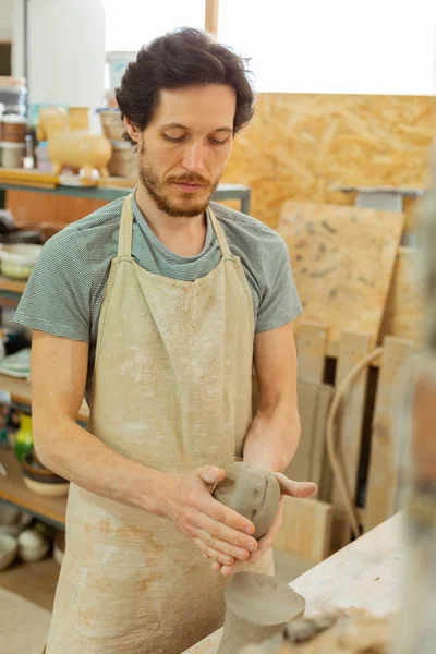 Спокійний професійний майстер глини розігріває кульку зі свіжої глини — стокове фото