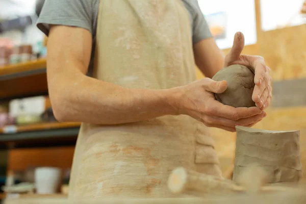 Maestro esperto con mani forti che rotolano argilla nella palla destra — Foto Stock