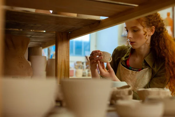 Good-looking long-haired ginger woman checking tiny clay cup — Stock Photo, Image