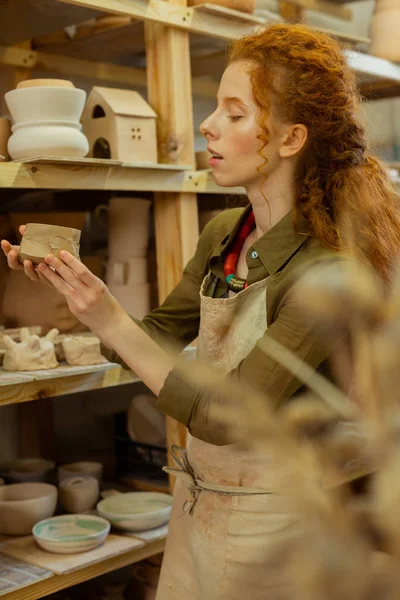 Menina gengibre atencioso desfrutando de diferentes figuras de argila e vasos — Fotografia de Stock
