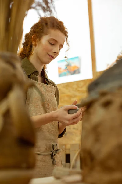 Pleasant good-looking girl peacefully warming up piece of clay — Stock Photo, Image