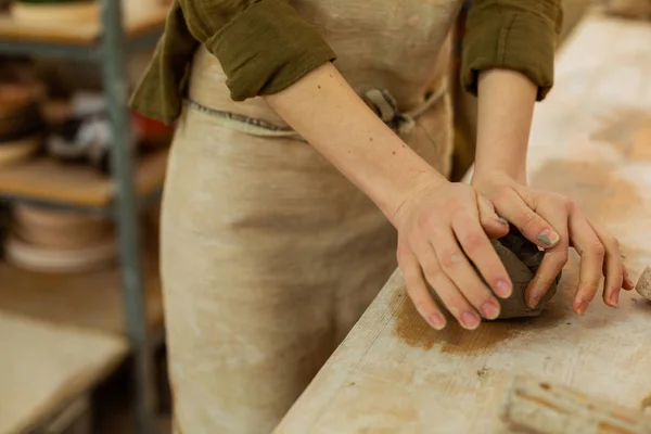 Accurate woman in protective apron dealing with wet clay — Stock Photo, Image