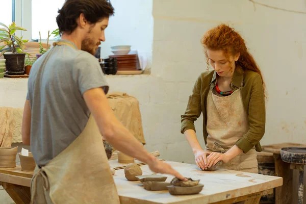 Curly attentive woman dealing with ball of clay — Stock Photo, Image