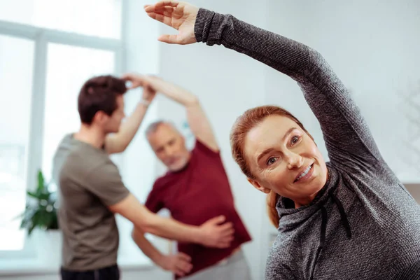 Mulher positiva agradável alegre fazendo exercícios físicos — Fotografia de Stock