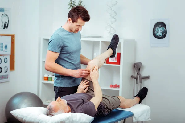 Handsome skilled man doing a leg massage — Stock Photo, Image