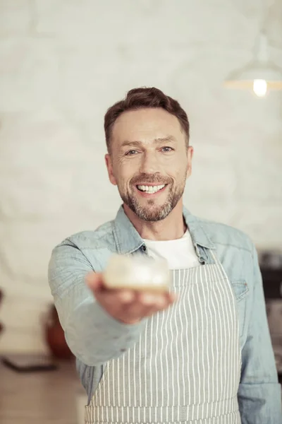 Barista sorridente sugerindo uma xícara de café . — Fotografia de Stock