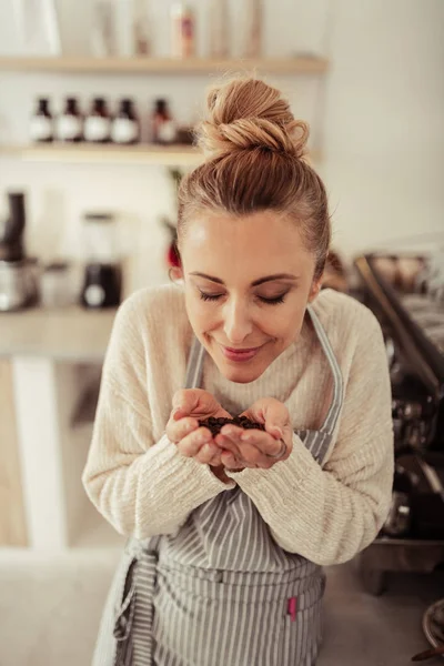 Leende kvinna luktar nyrostade kaffebönor. — Stockfoto