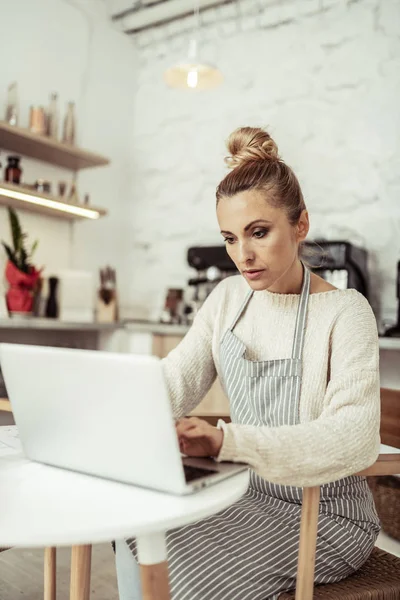 Konzentrierte Mitarbeiterin eines Cafés, die am Laptop arbeitet. — Stockfoto