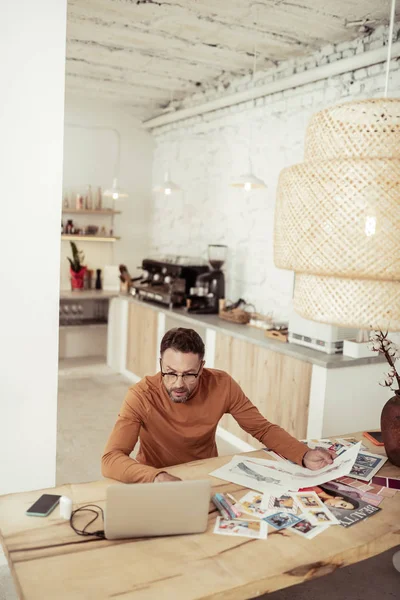 Diseñador sentado a la mesa y revisando sus obras . — Foto de Stock