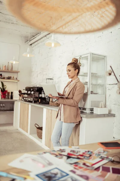 Smart woman working on her laptop near coffee machine. — Stock Photo, Image