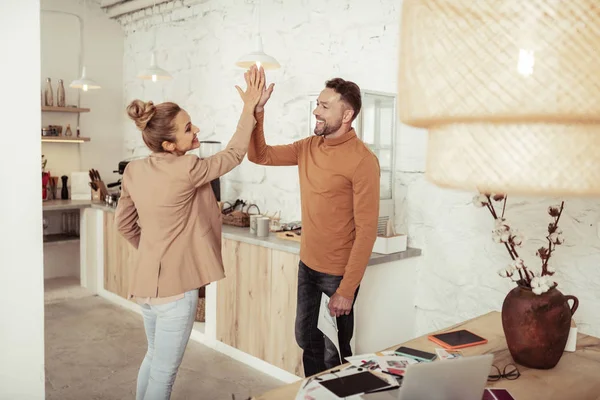 Adult colleagues smiling and high-fiving each other.