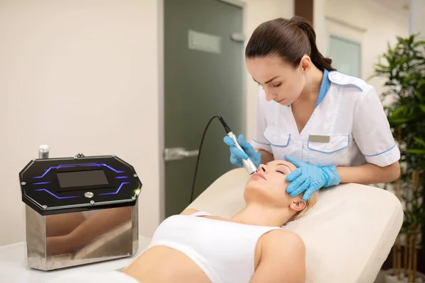 Dunkelhaarige Dermatologin bei einer Laser-Hautbehandlung für Frauen — Stockfoto
