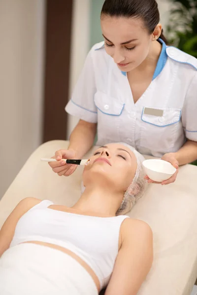 Dermatologo utilizzando pennello mentre mettere maschera sul client — Foto Stock