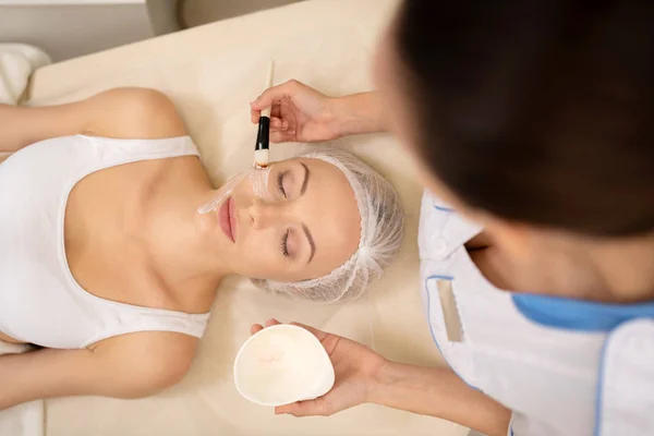 Dermatologe setzt Klientin Gesichtsmaske auf — Stockfoto