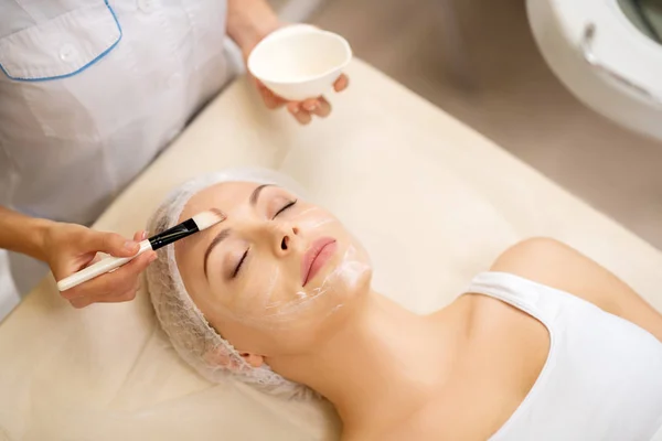 Frau schließt Augen, während Dermatologe Maske aufsetzt — Stockfoto
