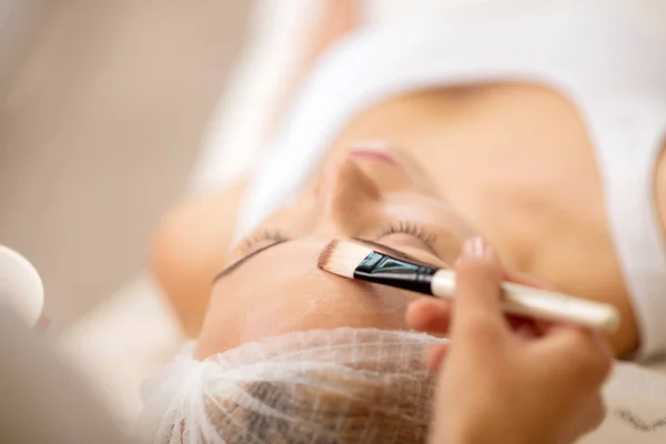 Close-up van cosmetoloog nemen cosmetica borstel met gezichtsmasker — Stockfoto