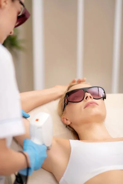 Mujer visitando salón depilatorio y disfrutando de depilación láser —  Fotos de Stock