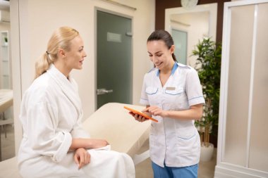 Kadın kozmetolojist müşteri ile gelecekteki randevu tartışıyor