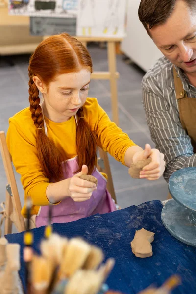 Chica pelirroja modelando figuras de arcilla con maestro — Foto de Stock