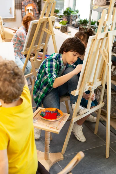 Grupo de talentosos alunos colorindo suas fotos na escola de arte — Fotografia de Stock