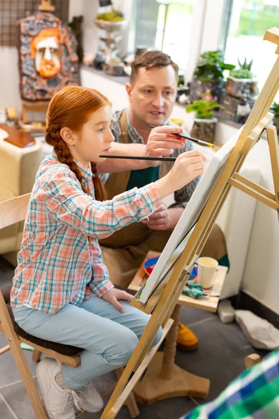 Schüler sitzt in der Nähe Staffelei Färbung Bild mit Lehrer — Stockfoto