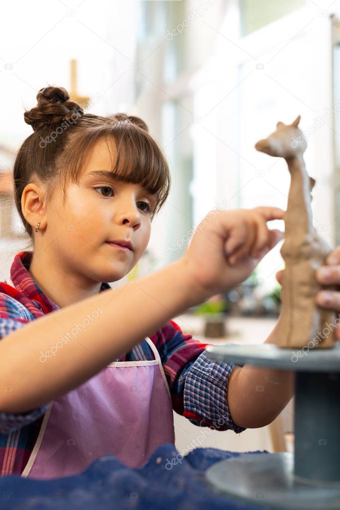 Talented girl modeling clay giraffe at the art lesson