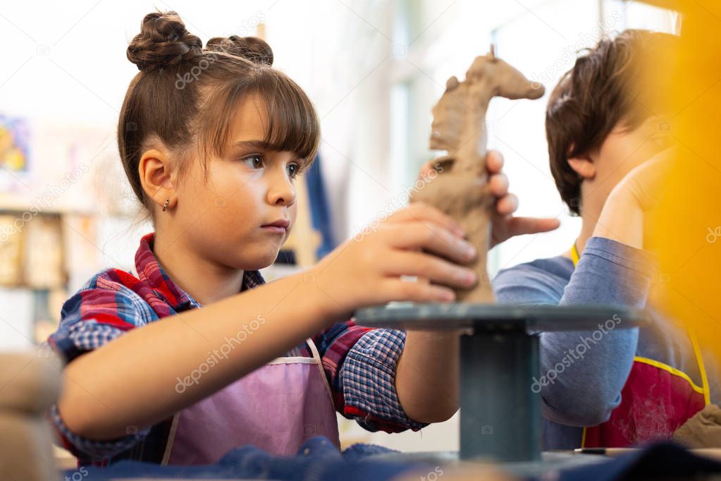 Girl feeling happy after making clay giraffe at art lesson