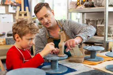 Sevimli çocuk küçük kil hayvan heykel öğretmeninin yanında oturan