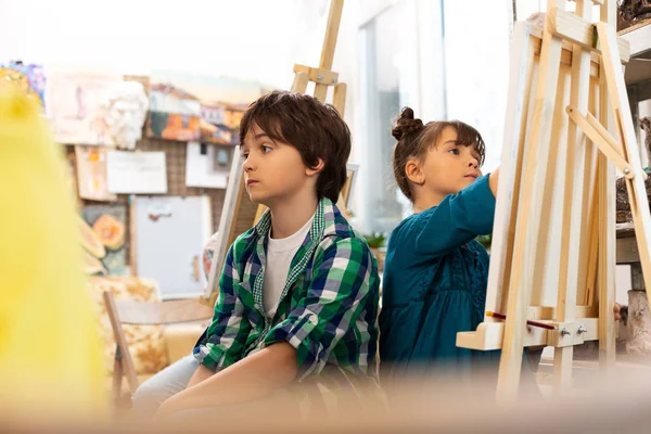 Dark-haired boy feeling bored during art lesson at school — Stock Photo, Image