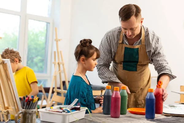 Erkek resim öğretmeni renkli boyalar ile sevimli küçük kız yardım — Stok fotoğraf